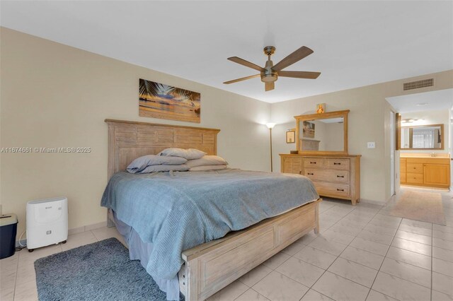 bedroom featuring ceiling fan, light tile patterned floors, and ensuite bath