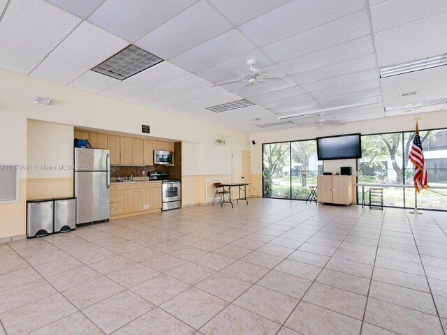 unfurnished living room with ceiling fan, light tile patterned floors, and a drop ceiling