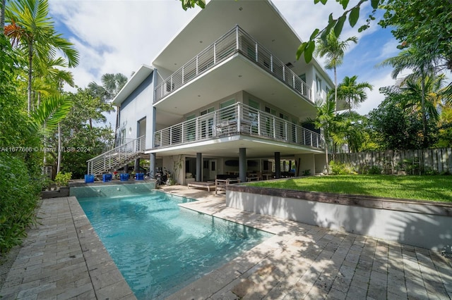 rear view of house featuring a fenced in pool, a patio area, and a lawn