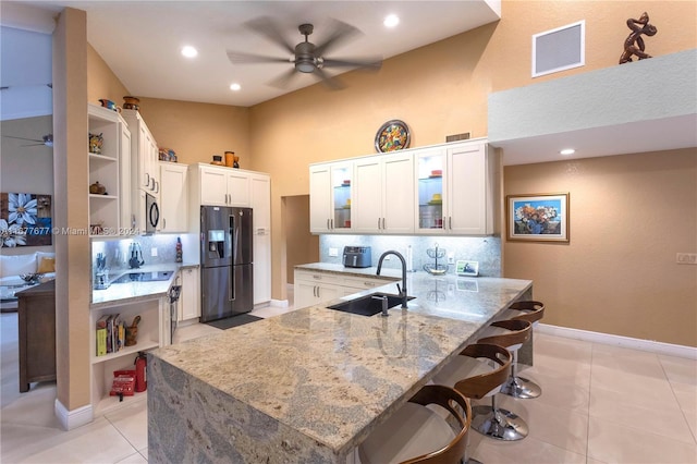 kitchen with kitchen peninsula, white cabinetry, sink, and black refrigerator with ice dispenser