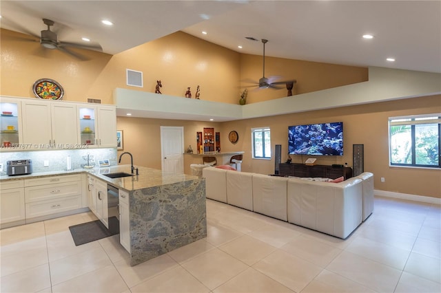 kitchen featuring light stone counters, sink, white cabinets, and a healthy amount of sunlight