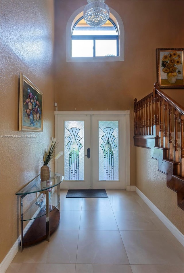 tiled entrance foyer with french doors, a notable chandelier, and a high ceiling