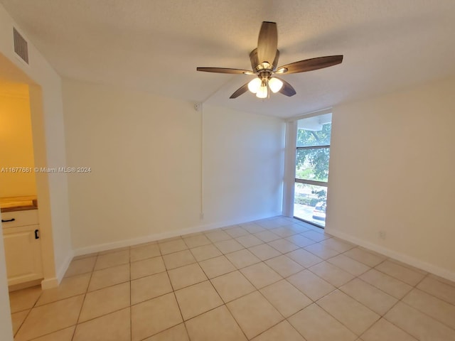 unfurnished room featuring a textured ceiling, light tile patterned floors, and ceiling fan