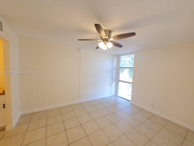 spare room with a textured ceiling, light tile patterned flooring, and ceiling fan