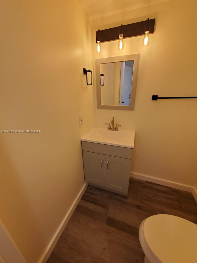 bathroom with toilet, vanity, and wood-type flooring