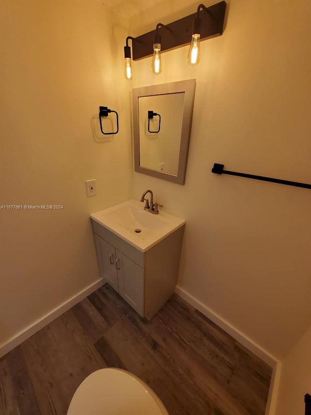 bathroom with vanity, toilet, and hardwood / wood-style floors