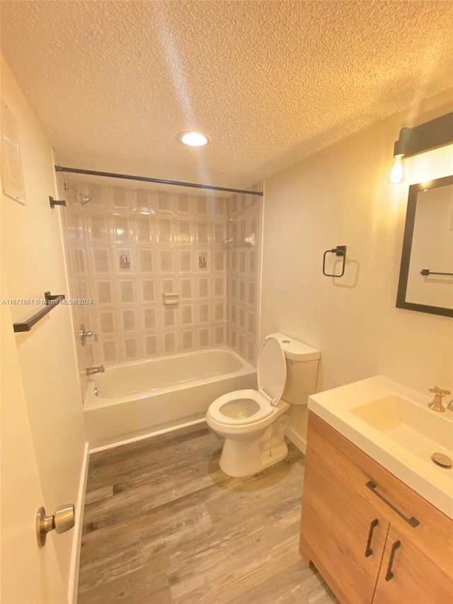 full bathroom with hardwood / wood-style flooring, toilet, shower / washtub combination, vanity, and a textured ceiling