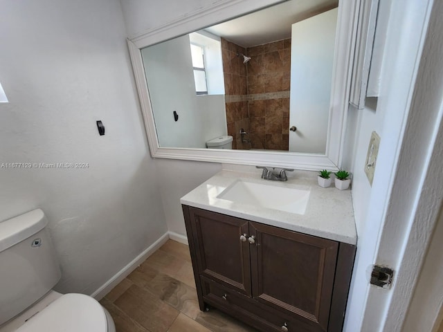 bathroom featuring vanity, tiled shower, and toilet