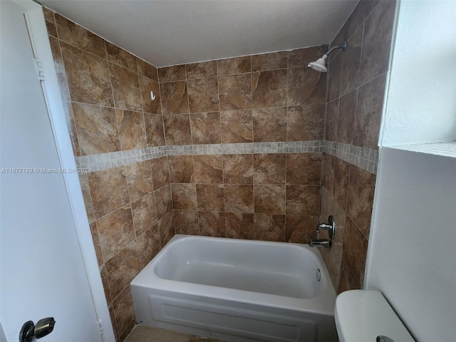 bathroom with toilet and tiled shower / bath