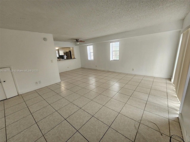 spare room with light tile patterned floors, a textured ceiling, and ceiling fan