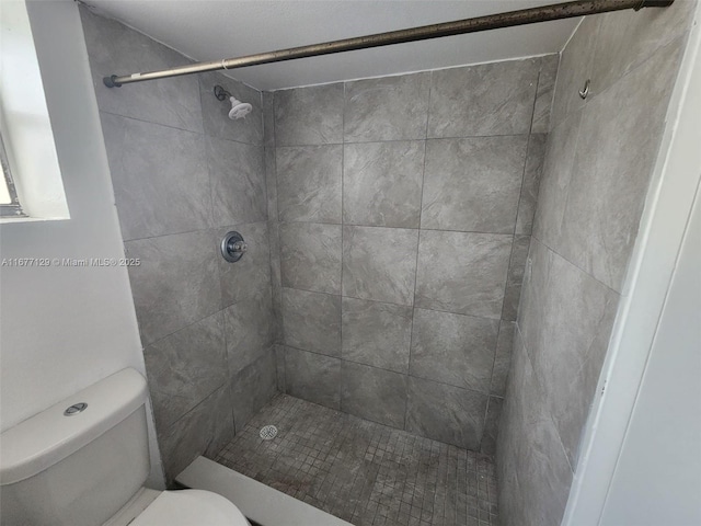 bathroom featuring a tile shower and toilet