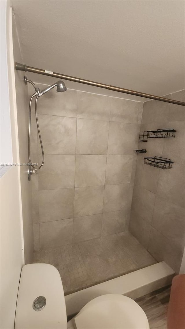 bathroom featuring a tile shower and toilet