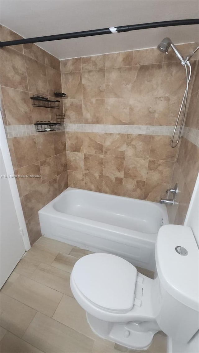 bathroom featuring toilet, tiled shower / bath combo, and tile patterned flooring