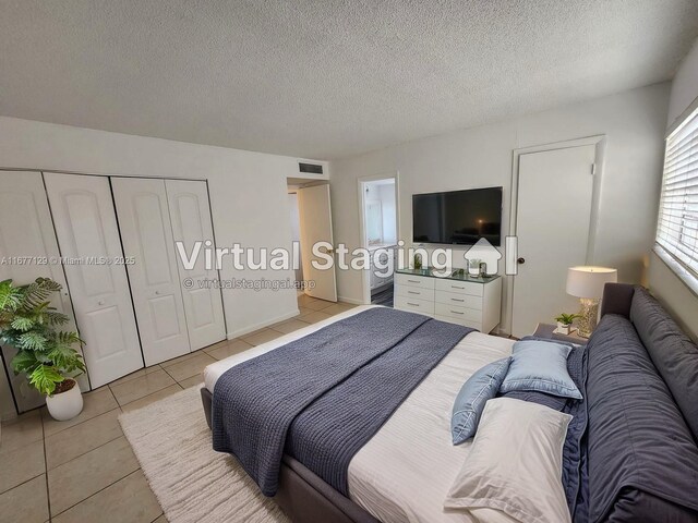 bedroom featuring a closet, a textured ceiling, and light tile patterned flooring