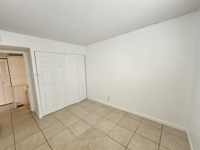 unfurnished bedroom with light tile patterned floors, a textured ceiling, and a closet