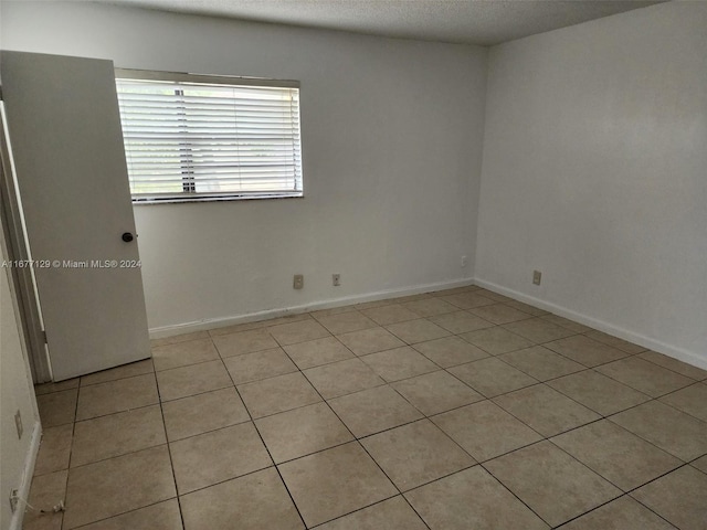 unfurnished room with a textured ceiling and light tile patterned floors