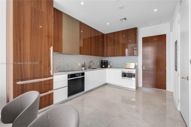 kitchen featuring tasteful backsplash, stainless steel oven, and sink