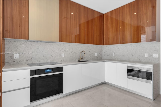 kitchen featuring oven, black electric stovetop, white cabinets, and backsplash