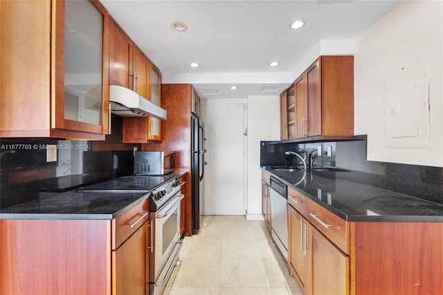 kitchen featuring electric panel, stainless steel appliances, sink, and dark stone counters