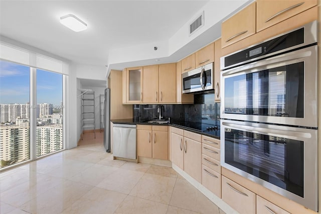 kitchen with backsplash, light brown cabinets, stainless steel appliances, and sink