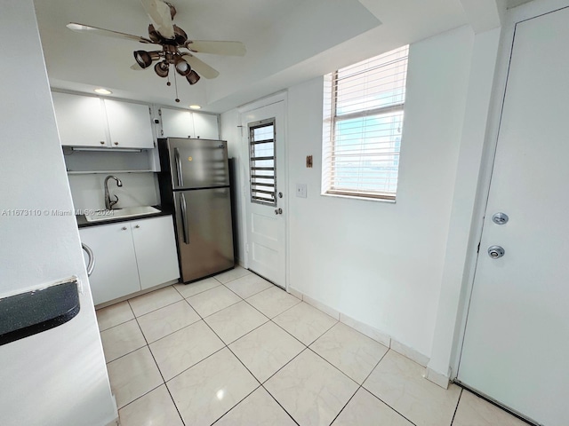 kitchen featuring white cabinets, stainless steel refrigerator, sink, and ceiling fan