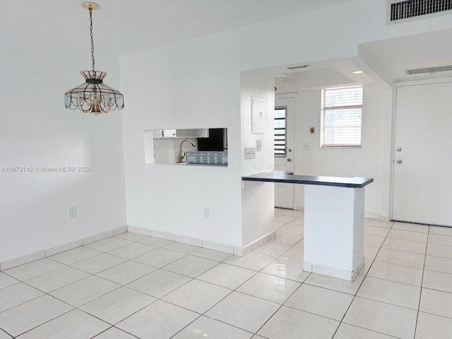 kitchen featuring kitchen peninsula, hanging light fixtures, light tile patterned flooring, and white cabinets