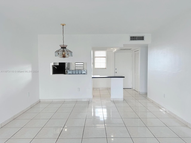 spare room featuring an inviting chandelier and light tile patterned floors