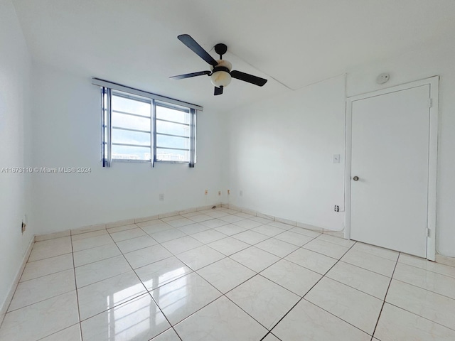 empty room with ceiling fan and light tile patterned floors