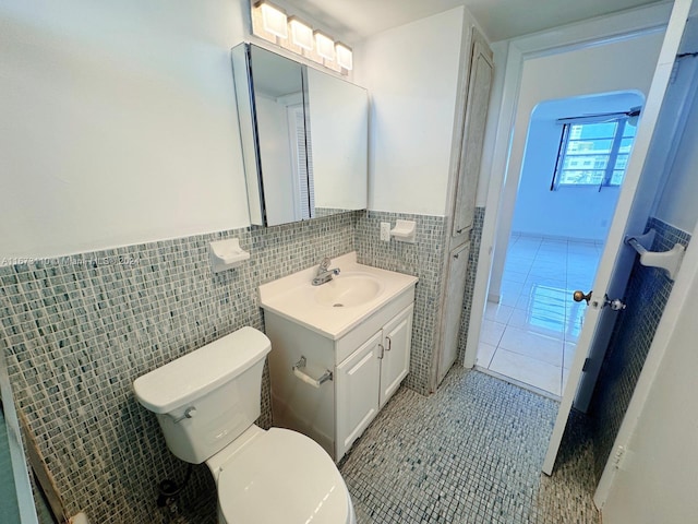 bathroom with tile patterned floors, vanity, toilet, and tile walls