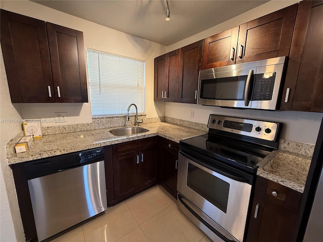 kitchen featuring light tile patterned floors, appliances with stainless steel finishes, a sink, a textured ceiling, and dark brown cabinets