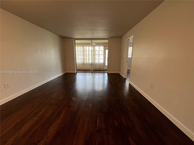 empty room featuring dark wood-type flooring and an inviting chandelier