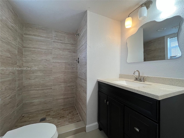 bathroom with toilet, vanity, and a tile shower