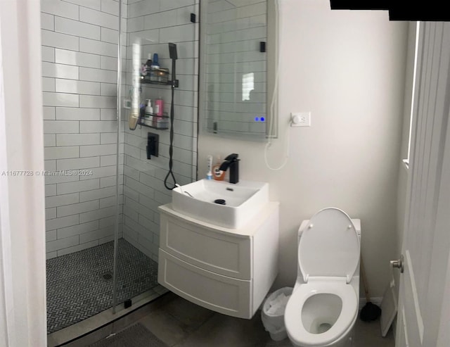 bathroom with vanity, toilet, and a tile shower