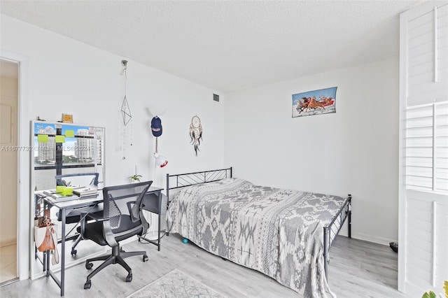 bedroom featuring light hardwood / wood-style floors and a textured ceiling