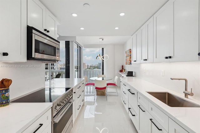 kitchen featuring decorative backsplash, white cabinets, light stone counters, appliances with stainless steel finishes, and sink