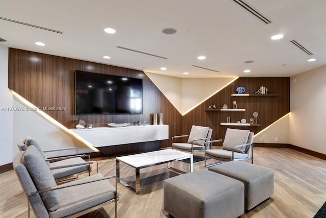 living room featuring light hardwood / wood-style flooring and wood walls