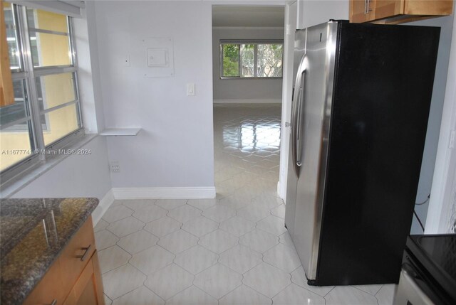 kitchen with dark stone counters and stainless steel refrigerator with ice dispenser