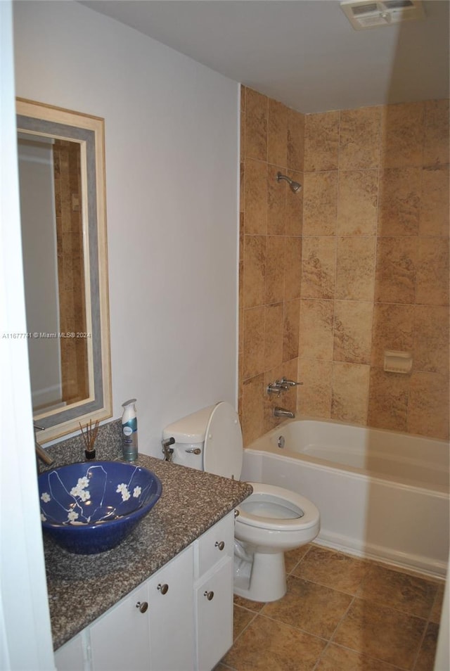 full bathroom with tile patterned flooring, vanity, tiled shower / bath combo, and toilet