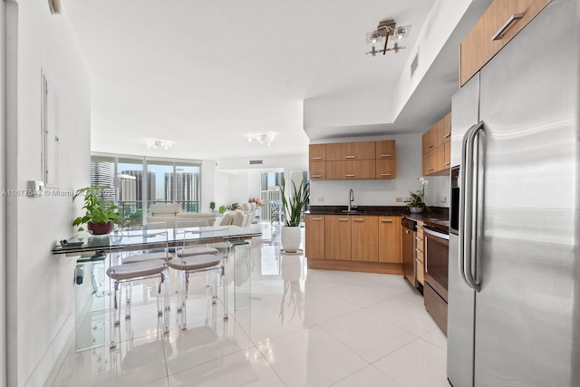 kitchen with sink, appliances with stainless steel finishes, a breakfast bar, and light tile patterned floors