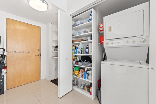 clothes washing area with light tile patterned floors and stacked washing maching and dryer