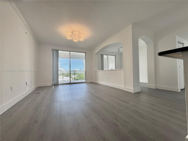 unfurnished living room featuring ornamental molding and dark hardwood / wood-style flooring