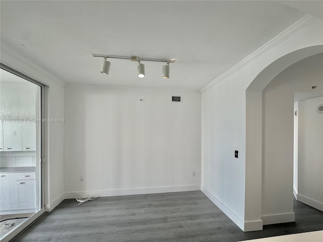 empty room featuring crown molding, track lighting, and wood-type flooring