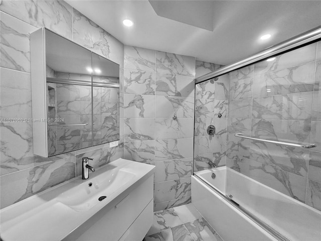 bathroom with vanity, enclosed tub / shower combo, and tile walls