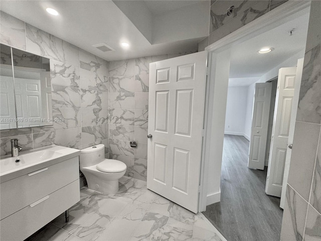 bathroom with tile walls, vanity, hardwood / wood-style floors, and toilet