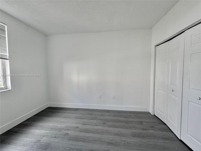 unfurnished bedroom featuring a closet, a textured ceiling, and dark hardwood / wood-style floors