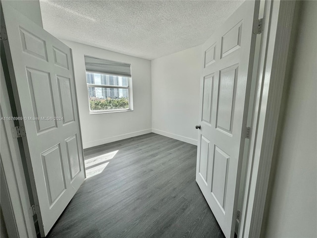 unfurnished bedroom with a textured ceiling and dark hardwood / wood-style flooring