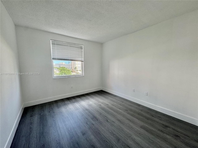 spare room with a textured ceiling and dark hardwood / wood-style flooring