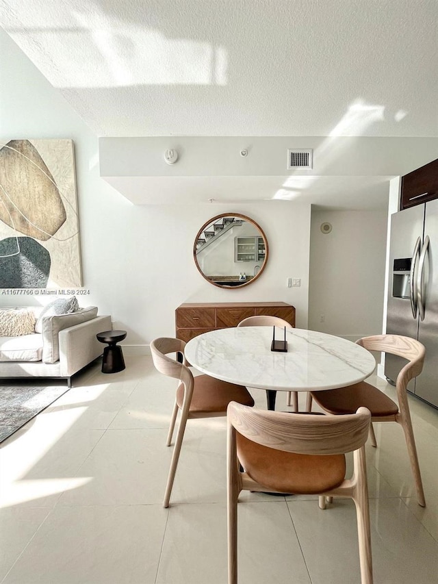 dining room featuring a textured ceiling and light tile patterned flooring