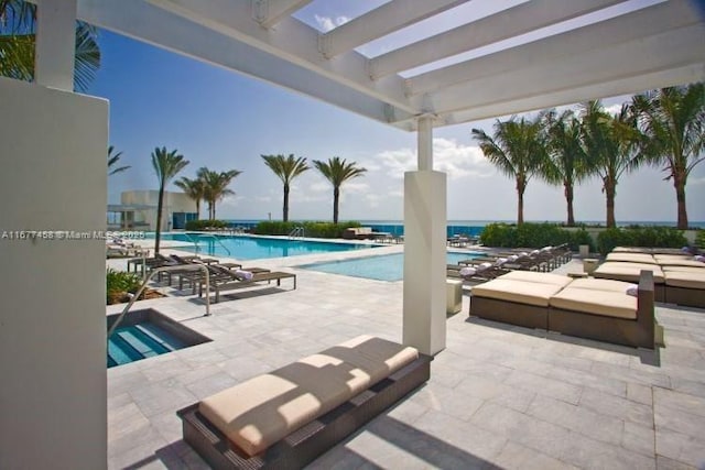 pool with a patio area and a hot tub