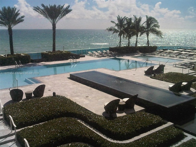 pool featuring a water view and a patio area